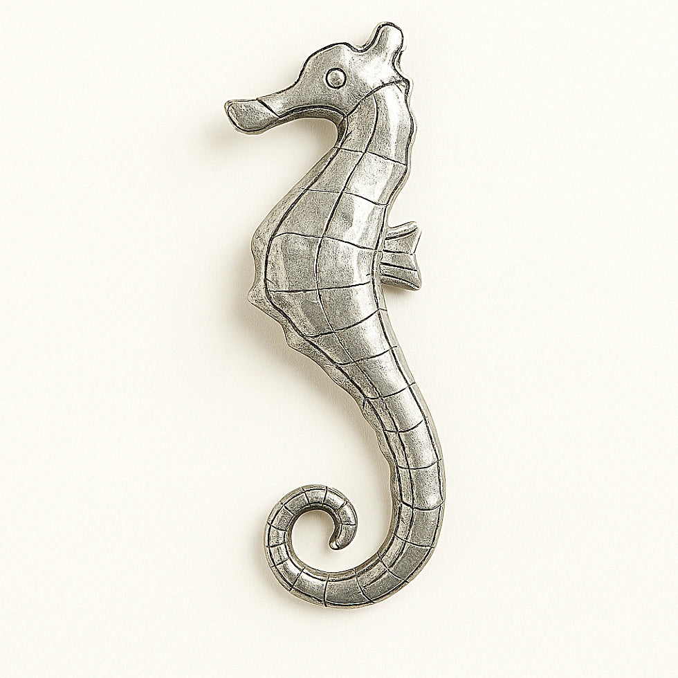 Decorative metal wall seahorse, silver-colored finish, on a pale background.