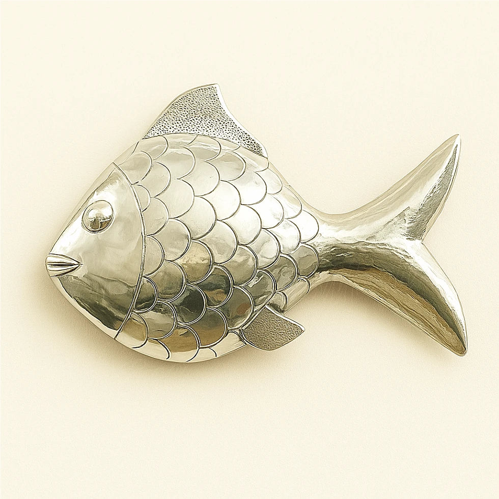 Decorative metal wall fish with engraved scales, silver-colored finish, on a pale background.
