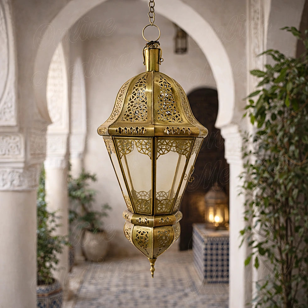 Handcrafted Moroccan brass lantern suspended in an arched interior with textured walls and greenery