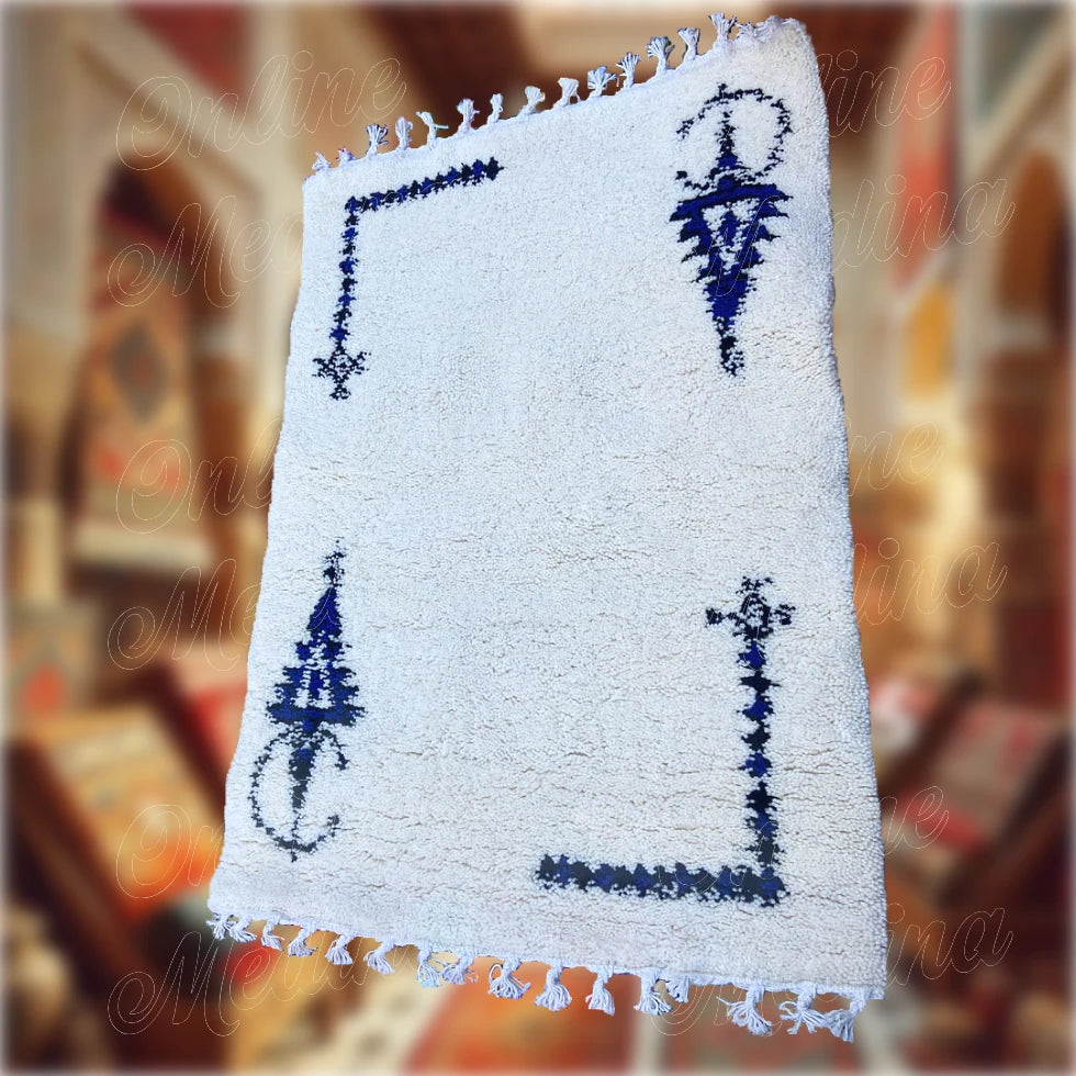 Handwoven Moroccan Khelala rug in cream wool with blue Berber designs — ideal for refined and cultural home decoration.