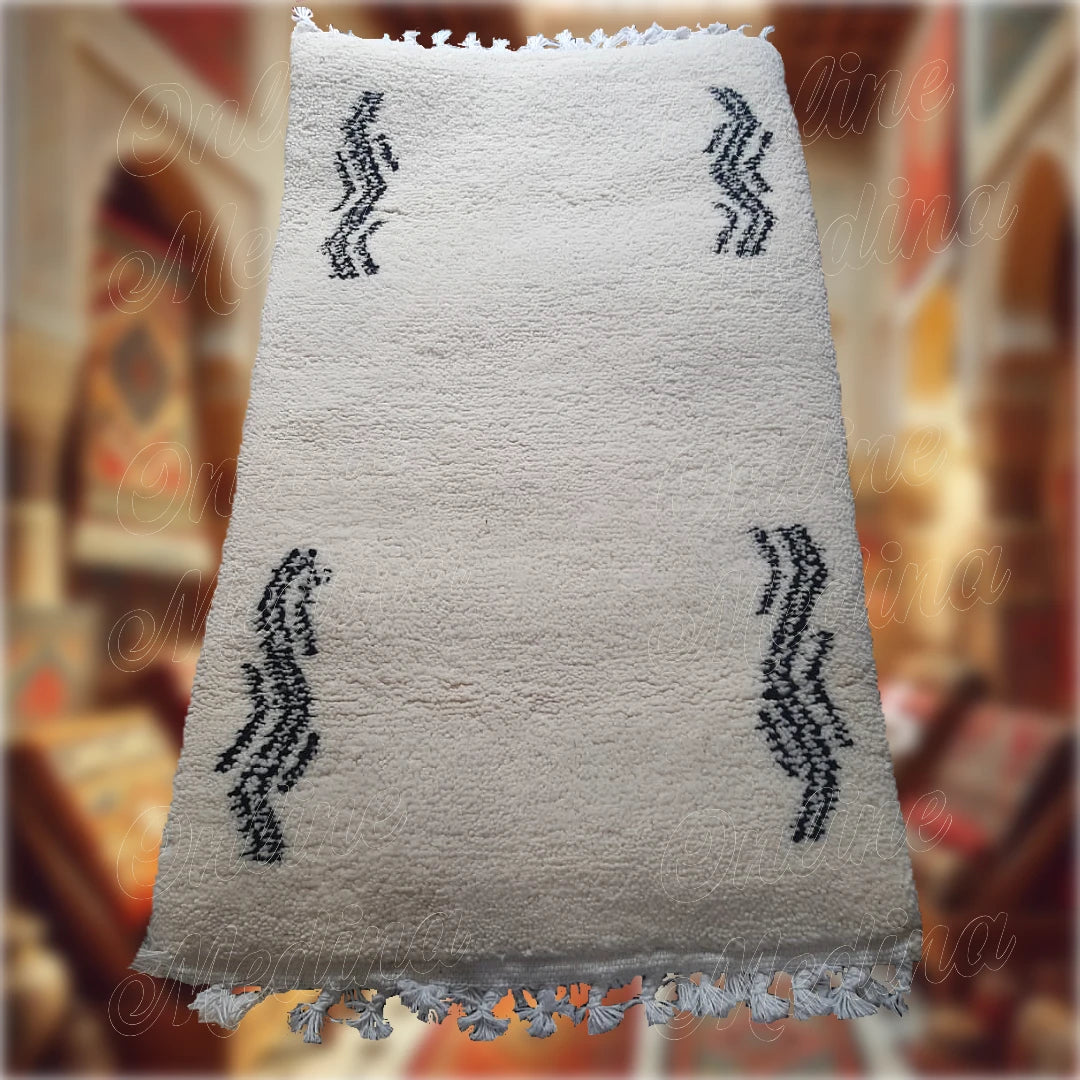 Tapis Serpenter artisanal marocain en laine blanche avec motifs ondulés noirs, fabriqué à la main, idéal pour une décoration intérieure moderne et minimaliste.