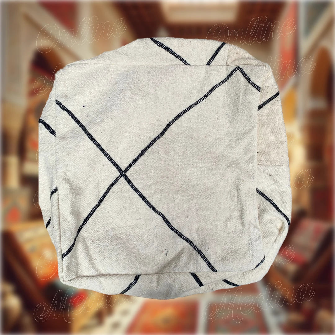 Pouf carré artisanal inspiré des tapis Beni Ouarain, avec motifs en losanges noirs sur fond blanc crème, fabriqué à la main en laine naturelle.