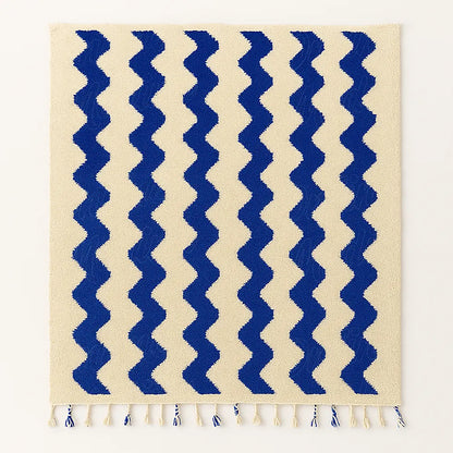 A handmade Moroccan wool rug with elegant blue wave motifs on a neutral wool base, ethically woven by artisans from Beni Mellal.