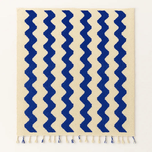 A handmade Moroccan wool rug with elegant blue wave motifs on a neutral wool base, ethically woven by artisans from Beni Mellal.