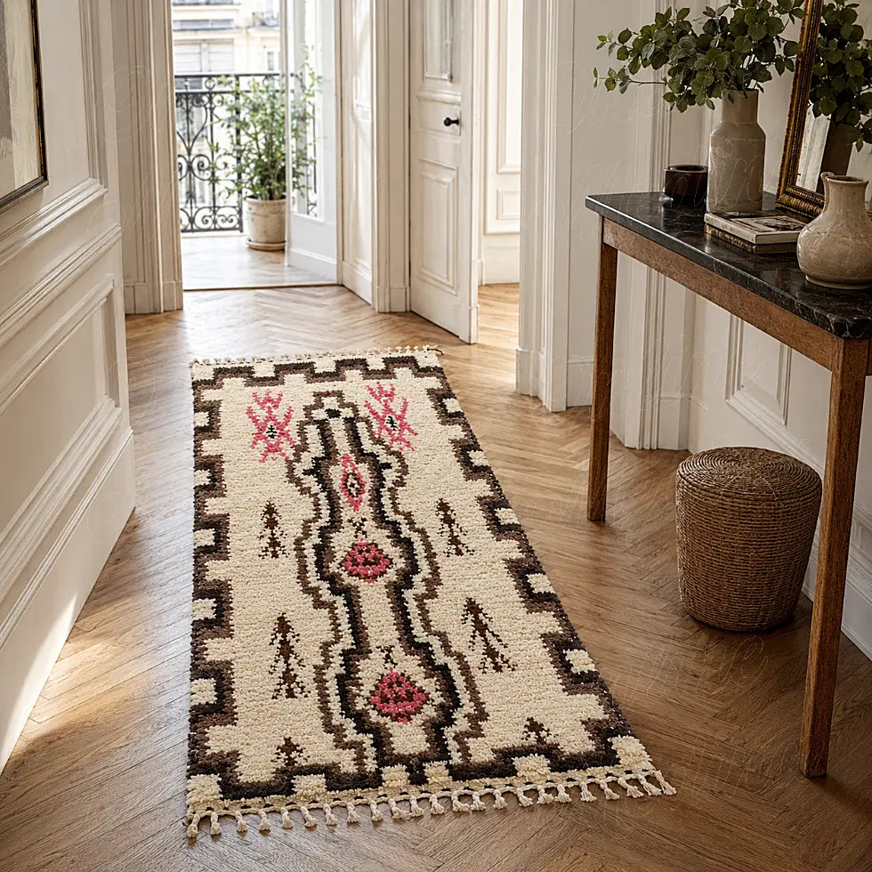 Tapis berbère écru à symboles framboise disposé dans un couloir parqueté près d’une console