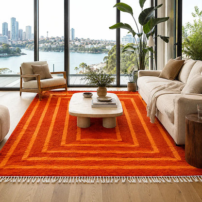 Tapis berbère moderne orange à rectangles concentriques devant un canapé clair dans un salon