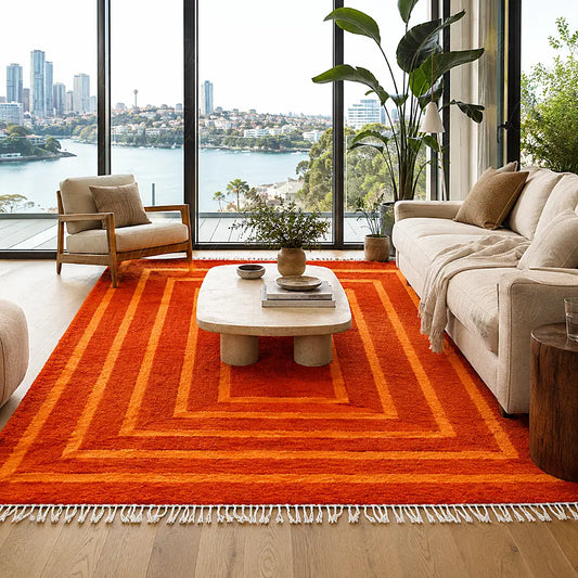 Tapis berbère moderne orange à rectangles concentriques devant un canapé clair dans un salon