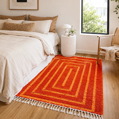 Tapis orange ton sur ton au pied d’un lit en bois dans une chambre lumineuse