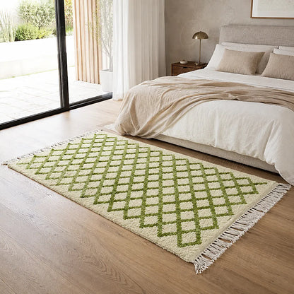 Tapis en laine écru à treillis vert placé au pied d’un lit dans une chambre lumineuse