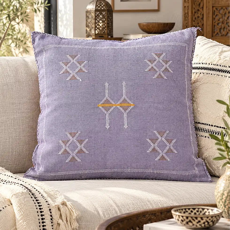 Coussin sabra lilas à motifs croisés posé sur un canapé clair
