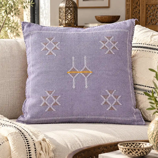 Coussin sabra lilas à motifs croisés posé sur un canapé clair