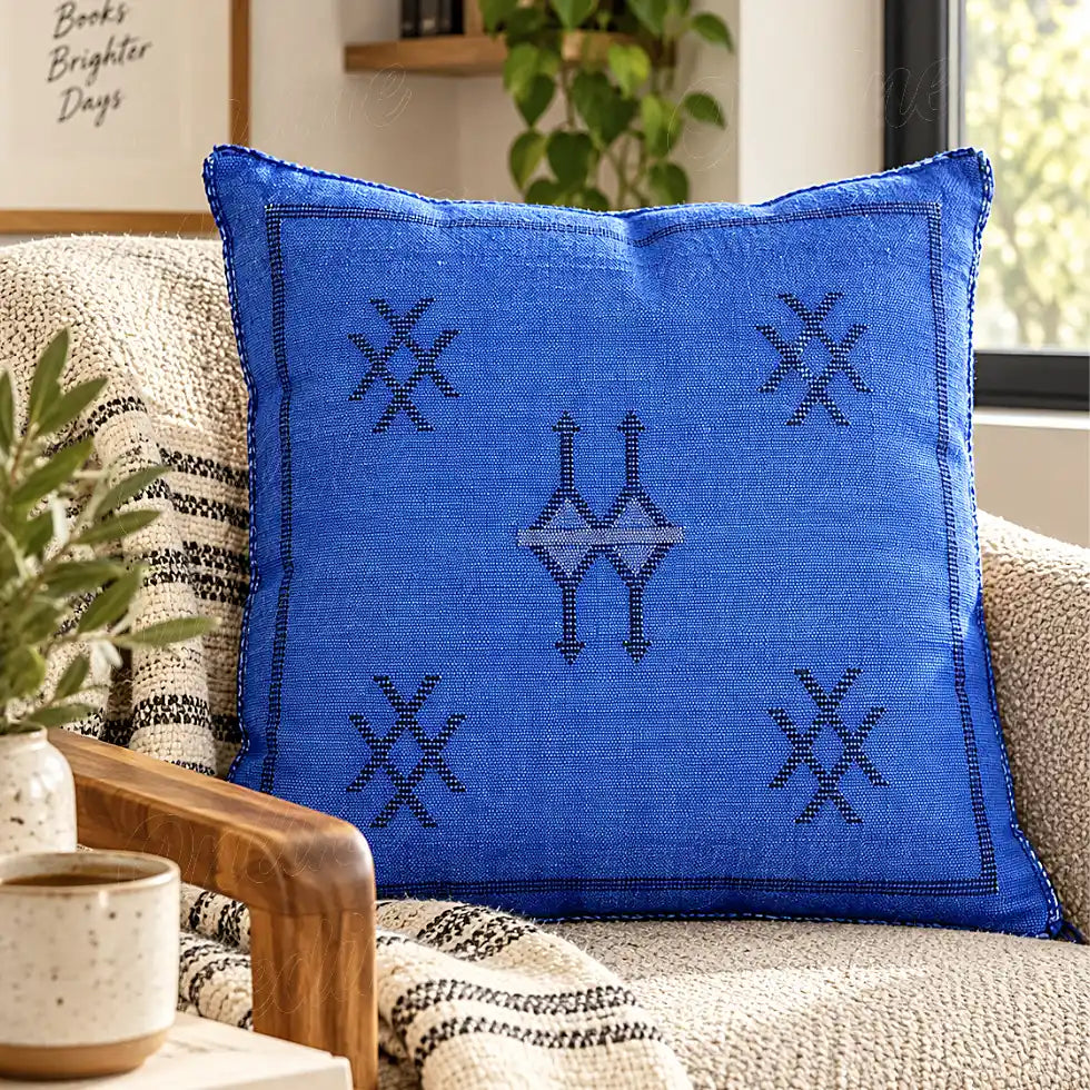 Coussin sabra bleu à motifs croisés sur un canapé tissé clair