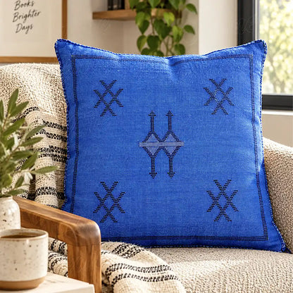 Coussin sabra bleu à motifs croisés sur un canapé tissé clair