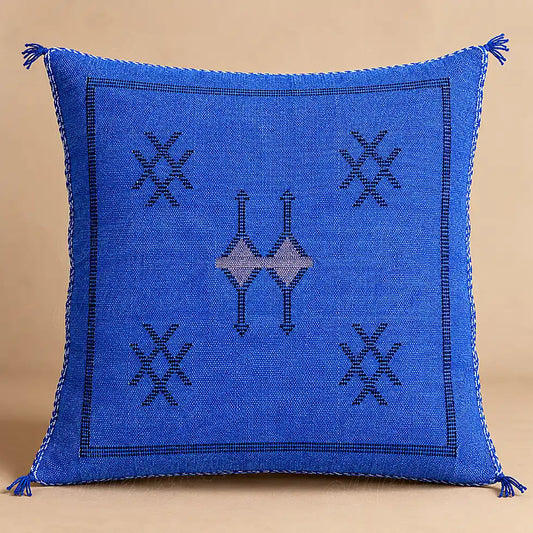 Coussin sabra bleu à motifs croisés présenté seul sur fond beige