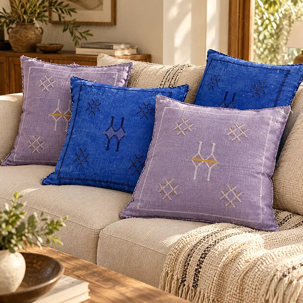 Quatre coussins sabra lilas et bleus à motifs croisés sur un canapé