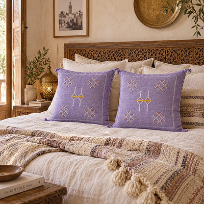 Deux coussins sabra lilas à motifs croisés disposés sur un grand lit