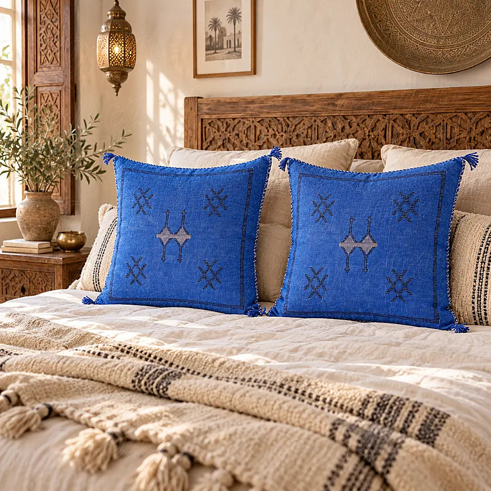 Deux coussins sabra bleus à motifs croisés disposés sur un grand lit