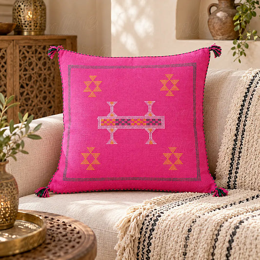 Coussin sabra rose fuchsia à bande centrale brodée sur un canapé clair