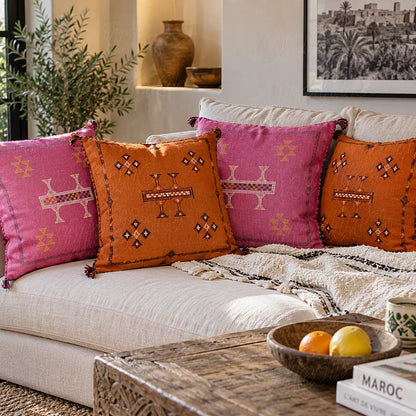 Quatre coussins sabra orange et fuchsia à motifs brodés sur un canapé