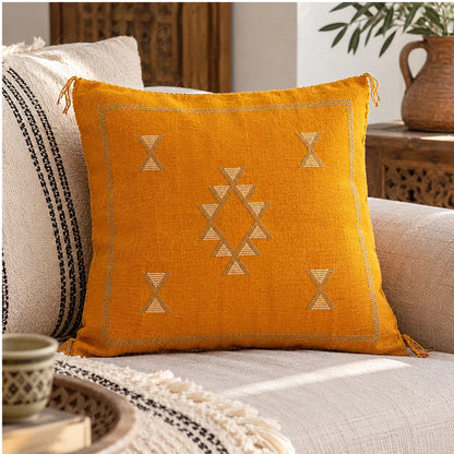 Coussin sabra jaune moutarde à losange ouvert posé sur un canapé clair