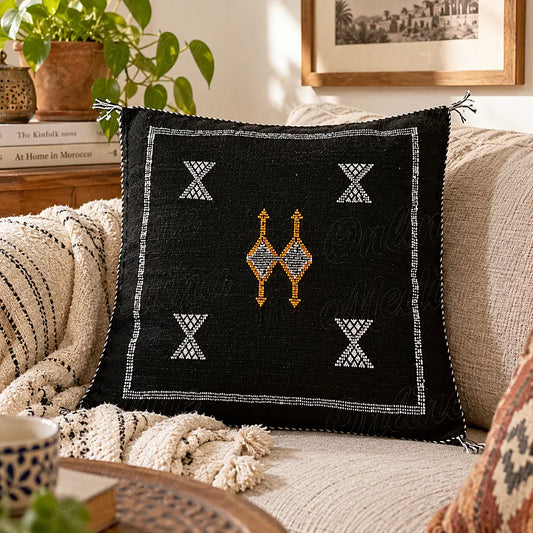 Coussin sabra noir à motifs angulaires contrastés sur un canapé clair