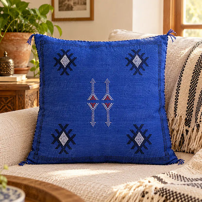 Coussin sabra bleu à motifs angulaires contrastés sur un canapé clair