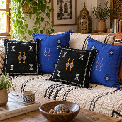 Quatre coussins sabra noirs et bleus à motifs contrastés sur un canapé
