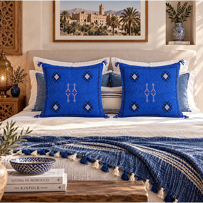 Deux coussins sabra bleus à motifs contrastés disposés sur un grand lit