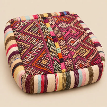 Pouf en laine bordeaux à motifs géométriques multicolores photographié seul sur fond uni