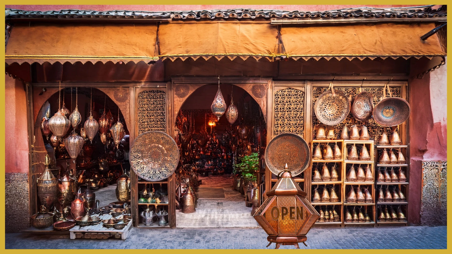 Traditional brassware shopfront in Marrakech displaying Moroccan lanterns, copper vases, and artisanal decor under a zellige arch.
