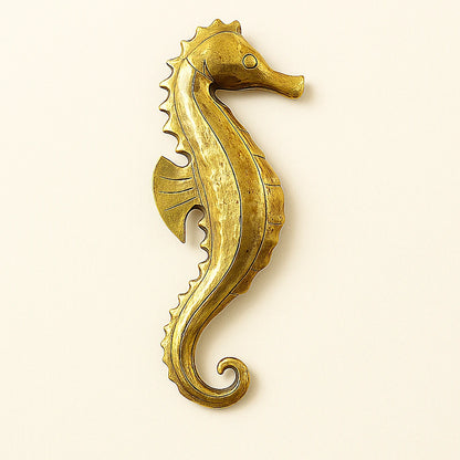 Handcrafted gold seahorse wall sculpture, hammered Moroccan metalwork on light background