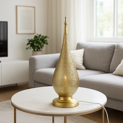 Oriental teardrop brass lamp with intricate cutwork, casting a warm golden glow in a bright modern living room.