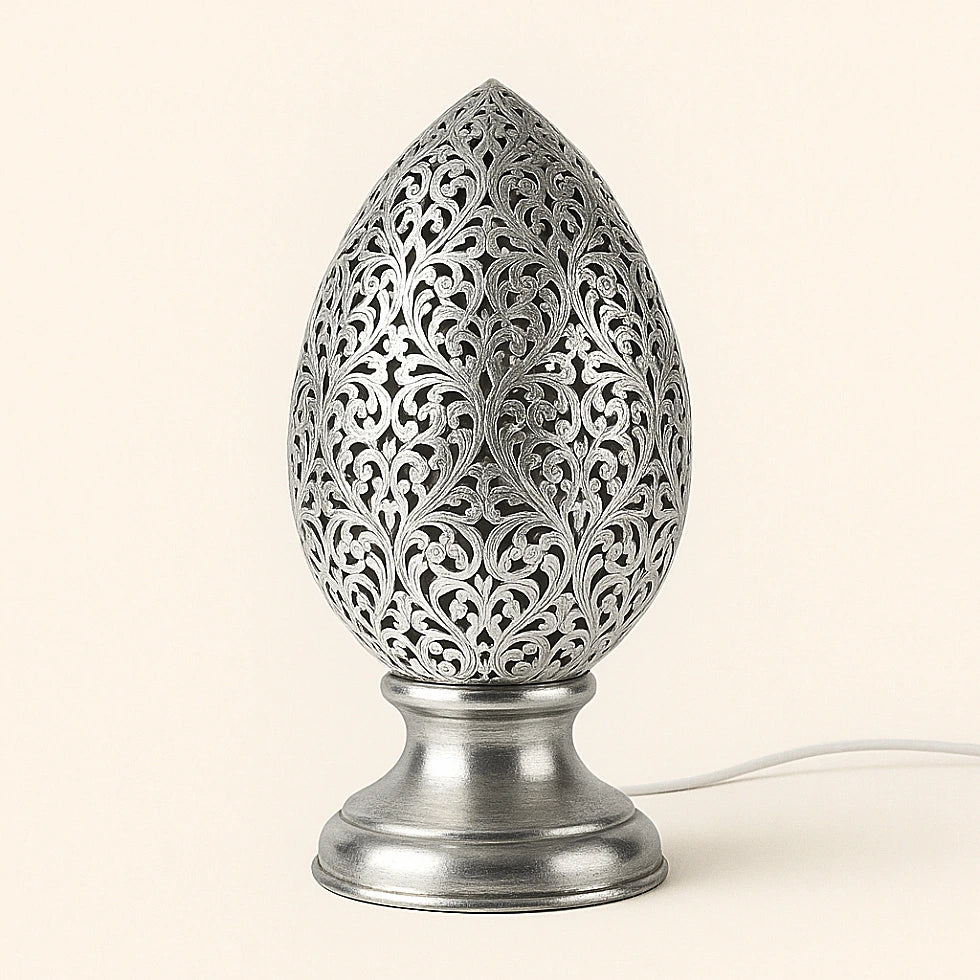 Silver-tin alloy Moroccan egg-shaped perforated table lamp with shiny finish and floral motifs on plain background