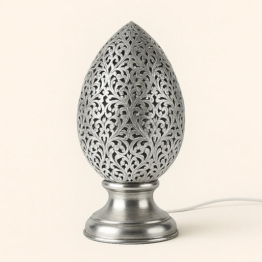 Silver-tin alloy Moroccan flame-shaped perforated table lamp with shiny finish and floral motifs on plain background