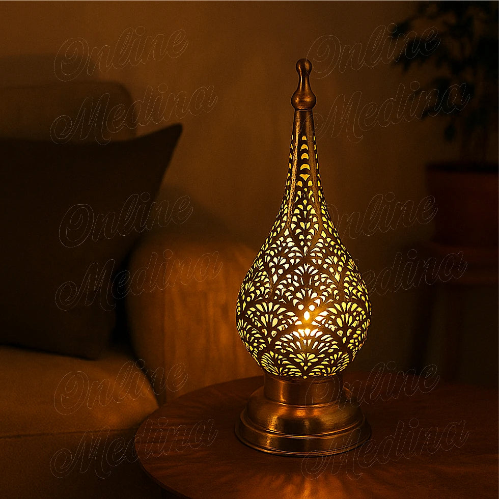 Lit Moroccan brass candle lantern glowing warmly through its oriental patterns at night.