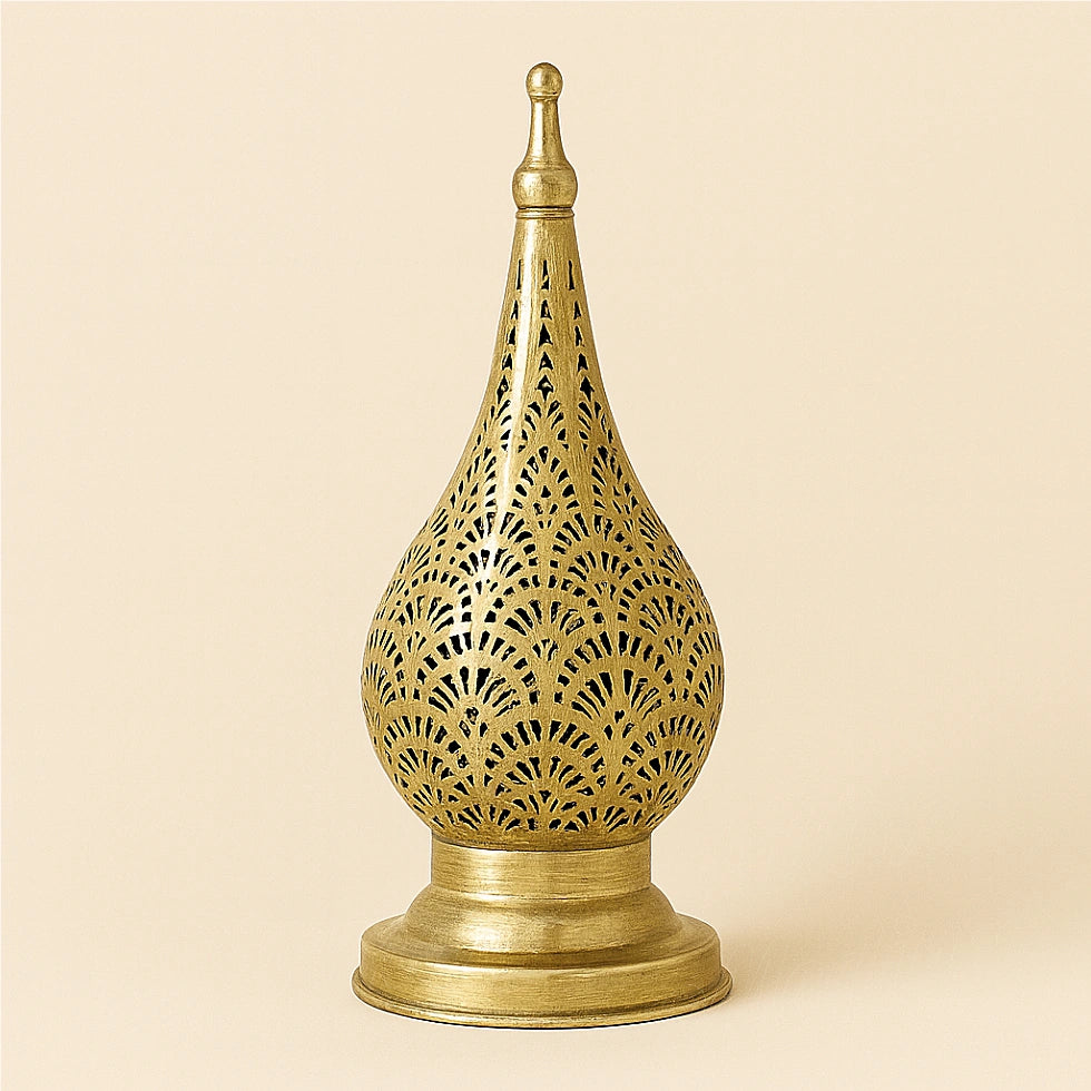 Brass Moroccan candle lantern with oriental openwork design on a plain beige background.