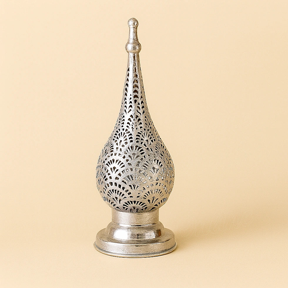 Silver Moroccan candle lantern with intricate pierced design on a plain beige background.
