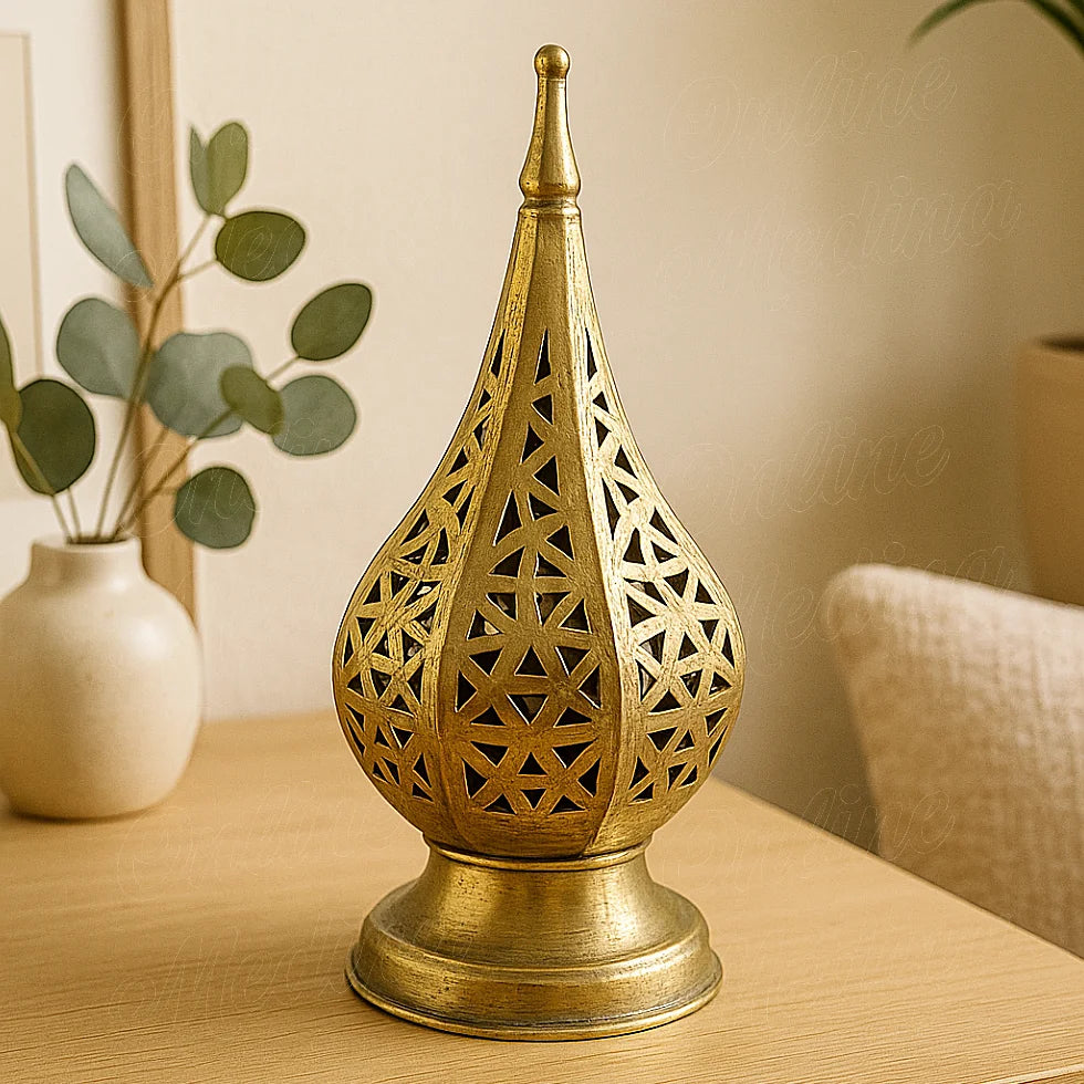 Moroccan brass geometric candle lantern with pierced design, placed on a wooden table in a bright living room.