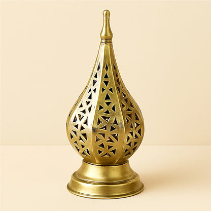 Brass Moroccan geometric candle lantern with intricate triangular cutouts on a plain beige background.