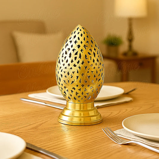 Portavelas de metal calado en forma de huevo, acabado dorado, sobre una mesa puesta.