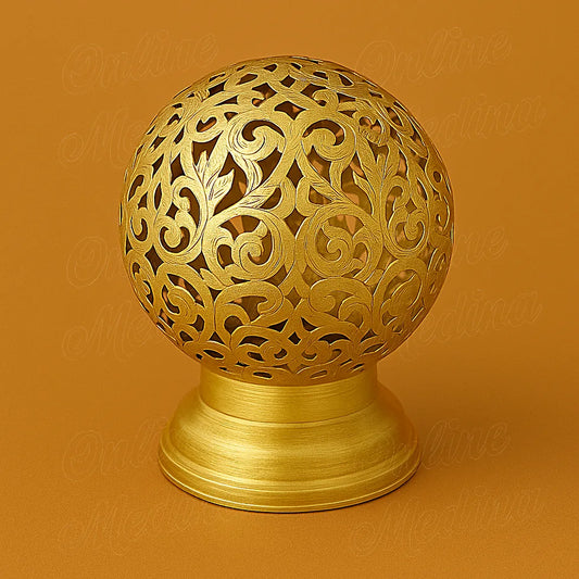 Bougeoir globe en métal ajouré, finition dorée, sur fond ocre.