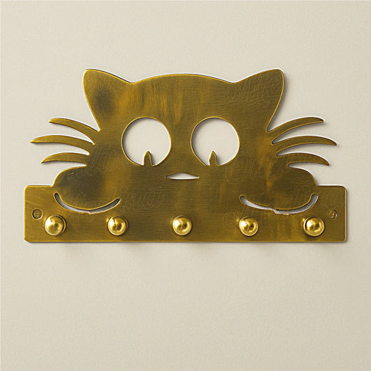 Brass cat-shaped wall key holder on light wall with round brass hooks