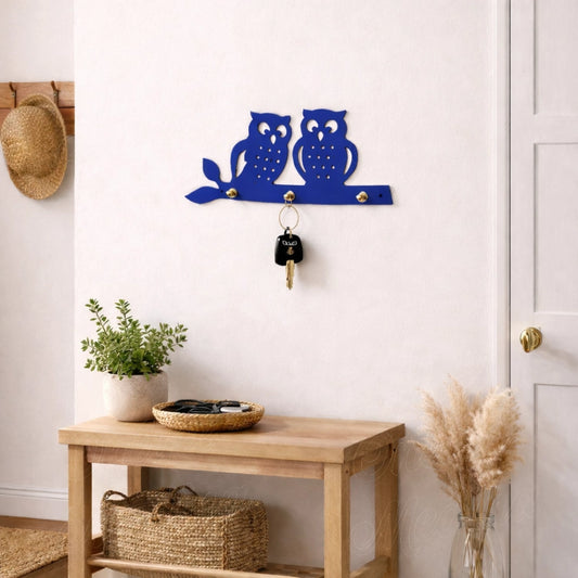 Blue owl wall key holder with brass knobs in minimalist entryway interior