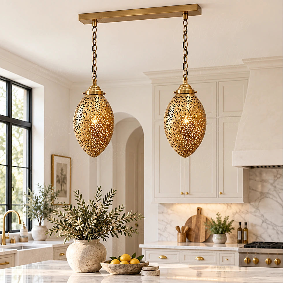 Two glowing openwork brass ovoid pendants on a rectangular canopy above a kitchen island