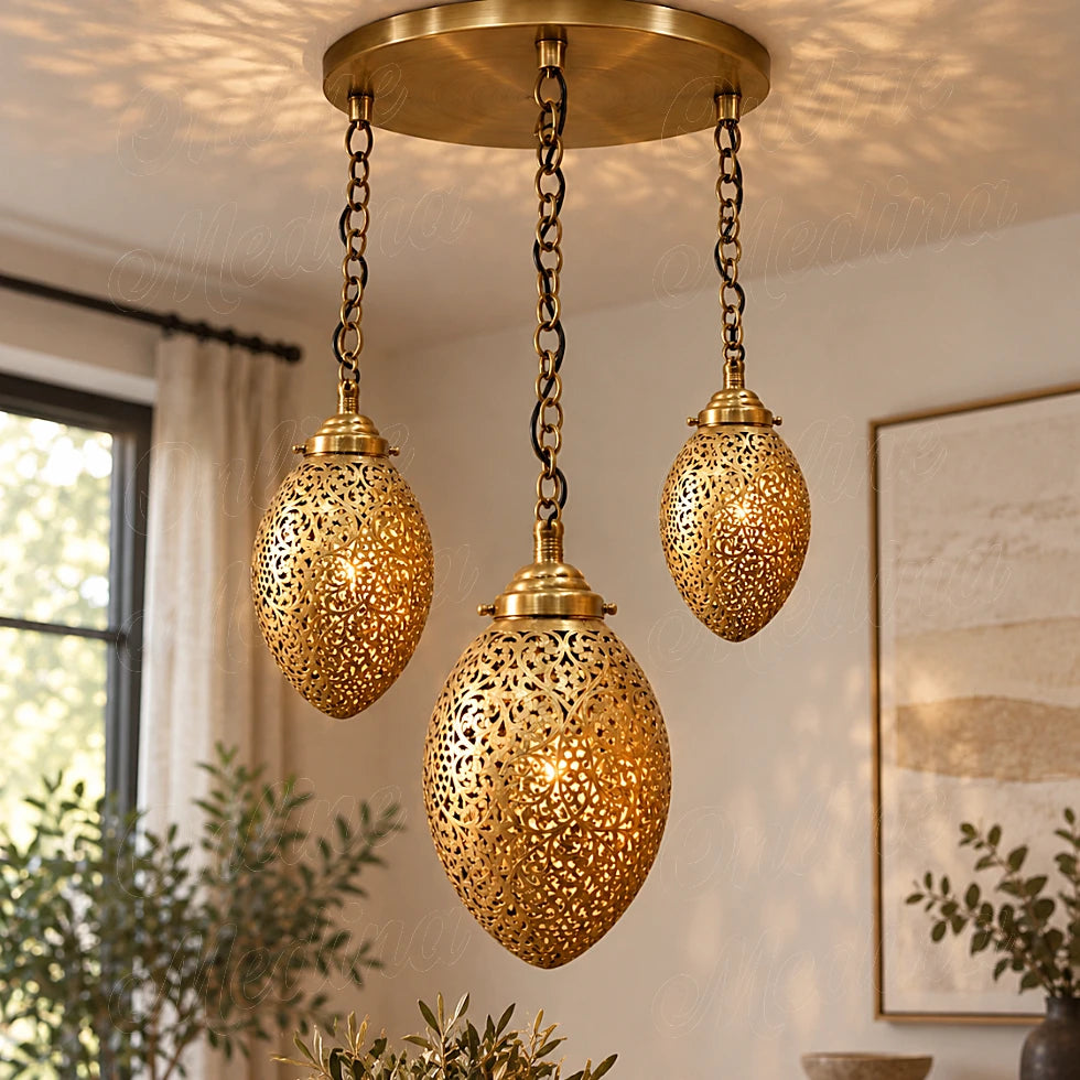 Three glowing brass ovoid pendants on a round canopy beside a window and framed wall art