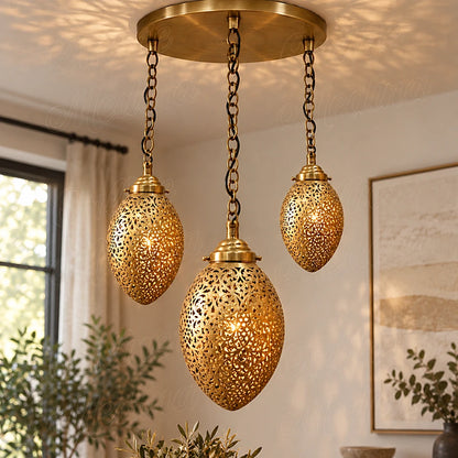Three glowing brass ovoid pendants on a round canopy beside a window and framed wall art