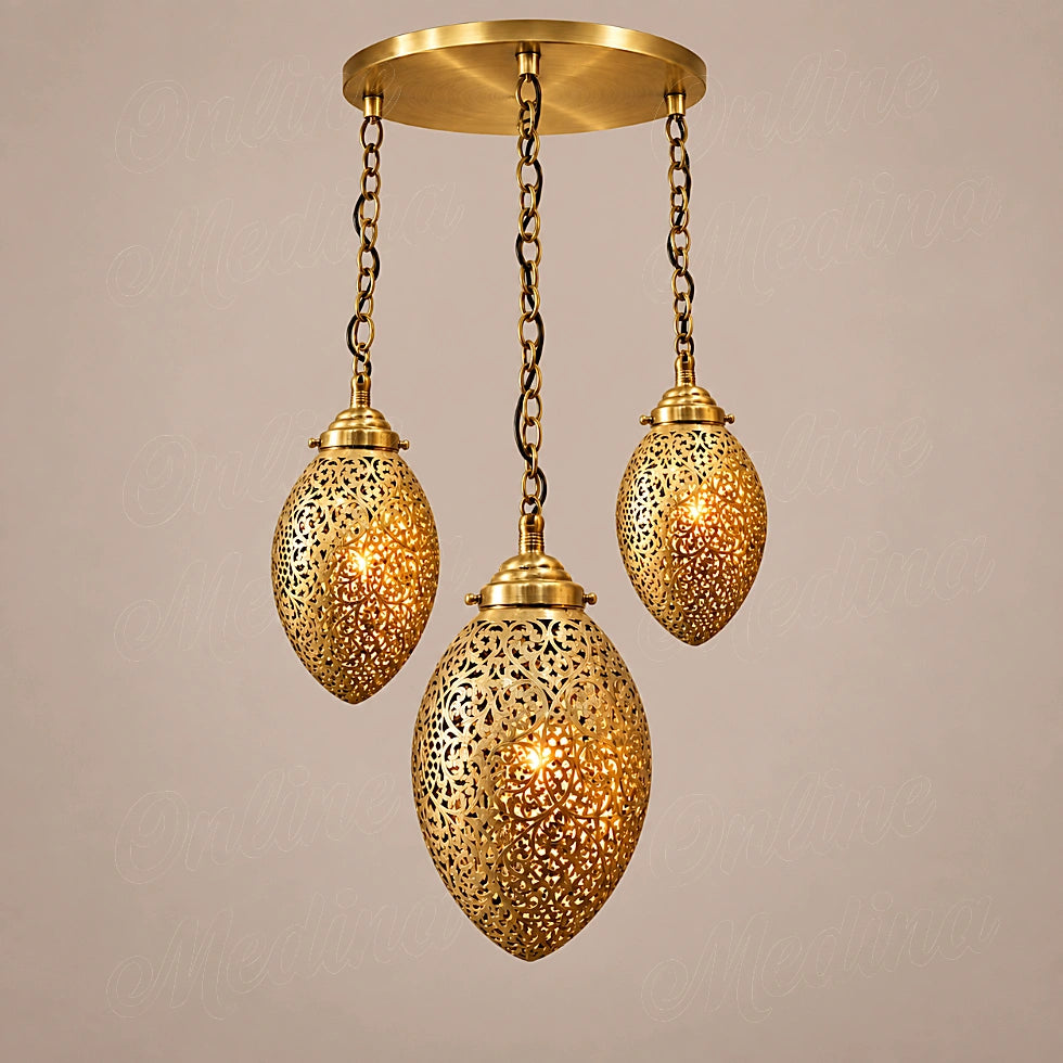 Three glowing brass ovoid pendants at staggered heights on a round canopy against a beige background