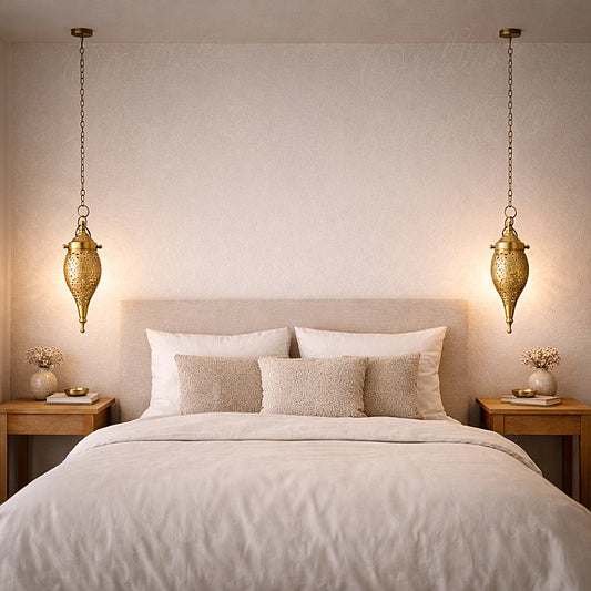 Handmade Moroccan brass teardrop pendant lights hanging above a bed in a calm minimalist bedroom setting
