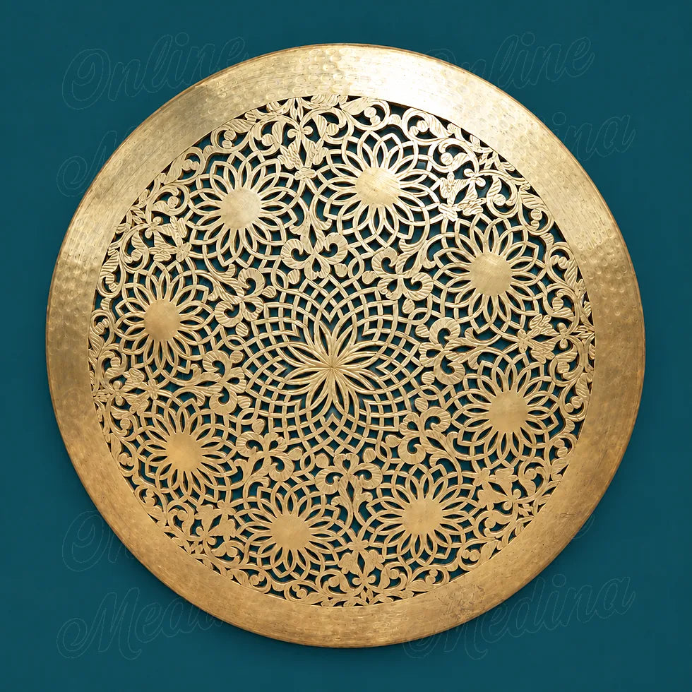 Round golden brass wall sconce with openwork floral rosettes and a wide hammered rim against a deep teal background.