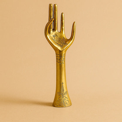 Handcrafted brass hand sculpture engraved with Moroccan floral motifs, displayed on a plain beige background